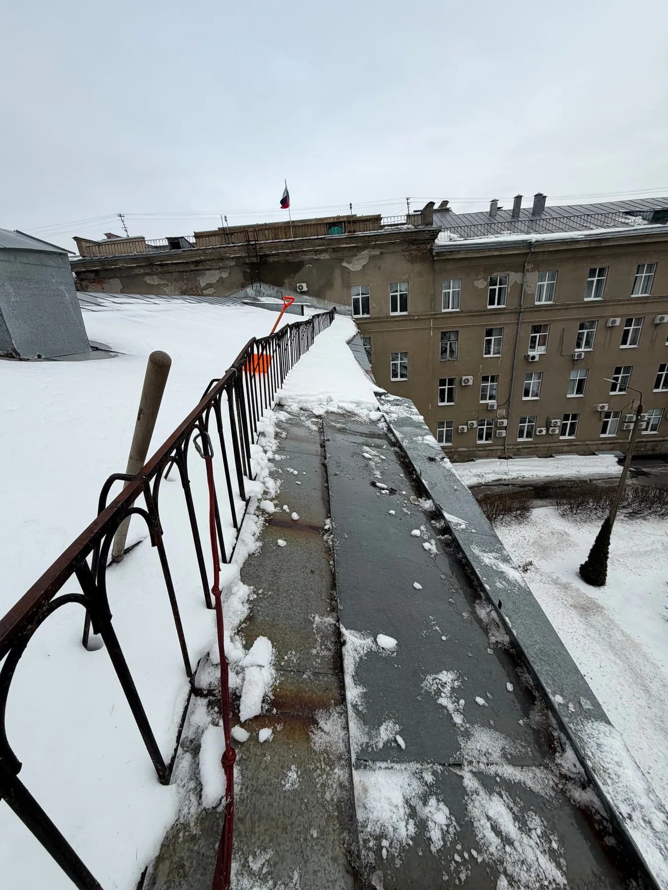 Очистка заснеженного участка кровли со страховочной верёвкой