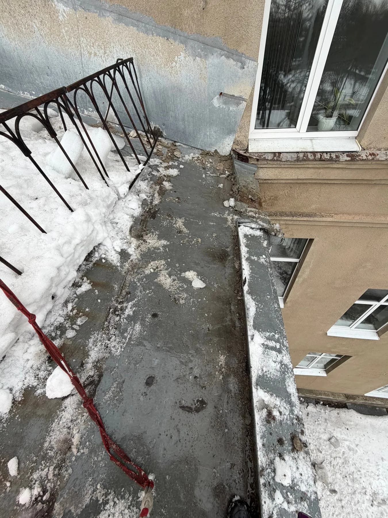 Очищаемый участок кровли у фасада со снегом и страховочной верёвкой
