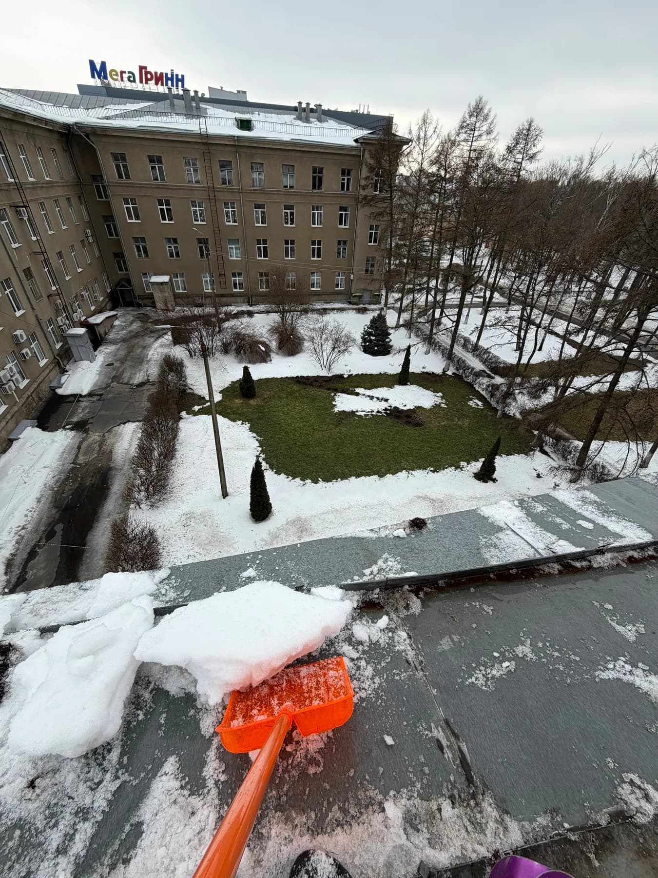 Очистка кровли от снега с видом на территорию здания
